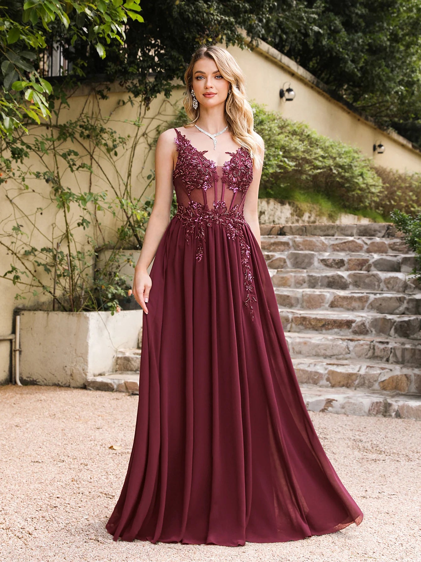 front view of girl outside wearing a burgundy luxury backless beaded a-line prom dress