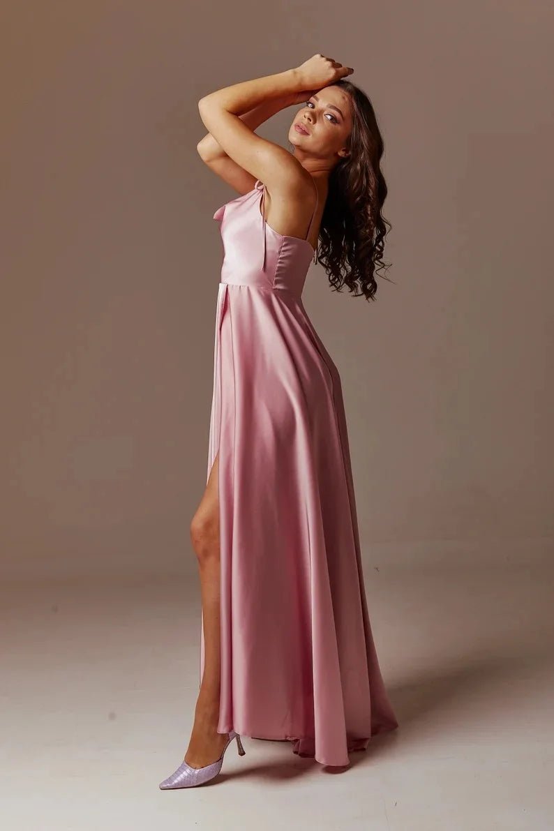 girl leaning back wearing dusty pink satin side slit backless prom dress with spaghetti straps