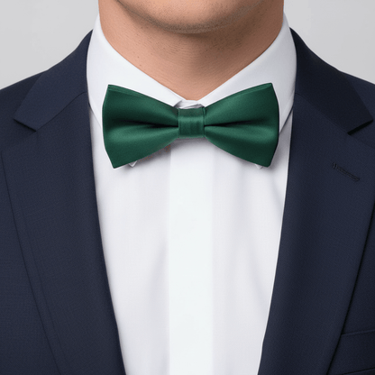 Green bow tie worn with a navy blazer and white shirt on a light gray background