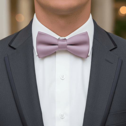 Man wearing a gray suit with a white shirt and purple bow tie.