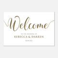 A rectangular white wedding welcome sign with elegant gold script reading “Welcome,” smaller gold text reading “TO THE WEDDING OF REBECCA & DARREN,” and the date “08.08.
