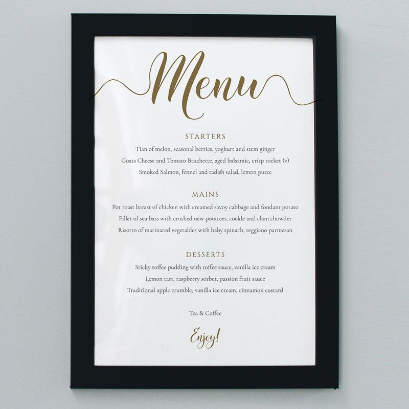 gold wedding menu print in a black picture frame