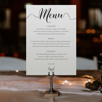 Elegant dinner menu in a metal stand on wedding table