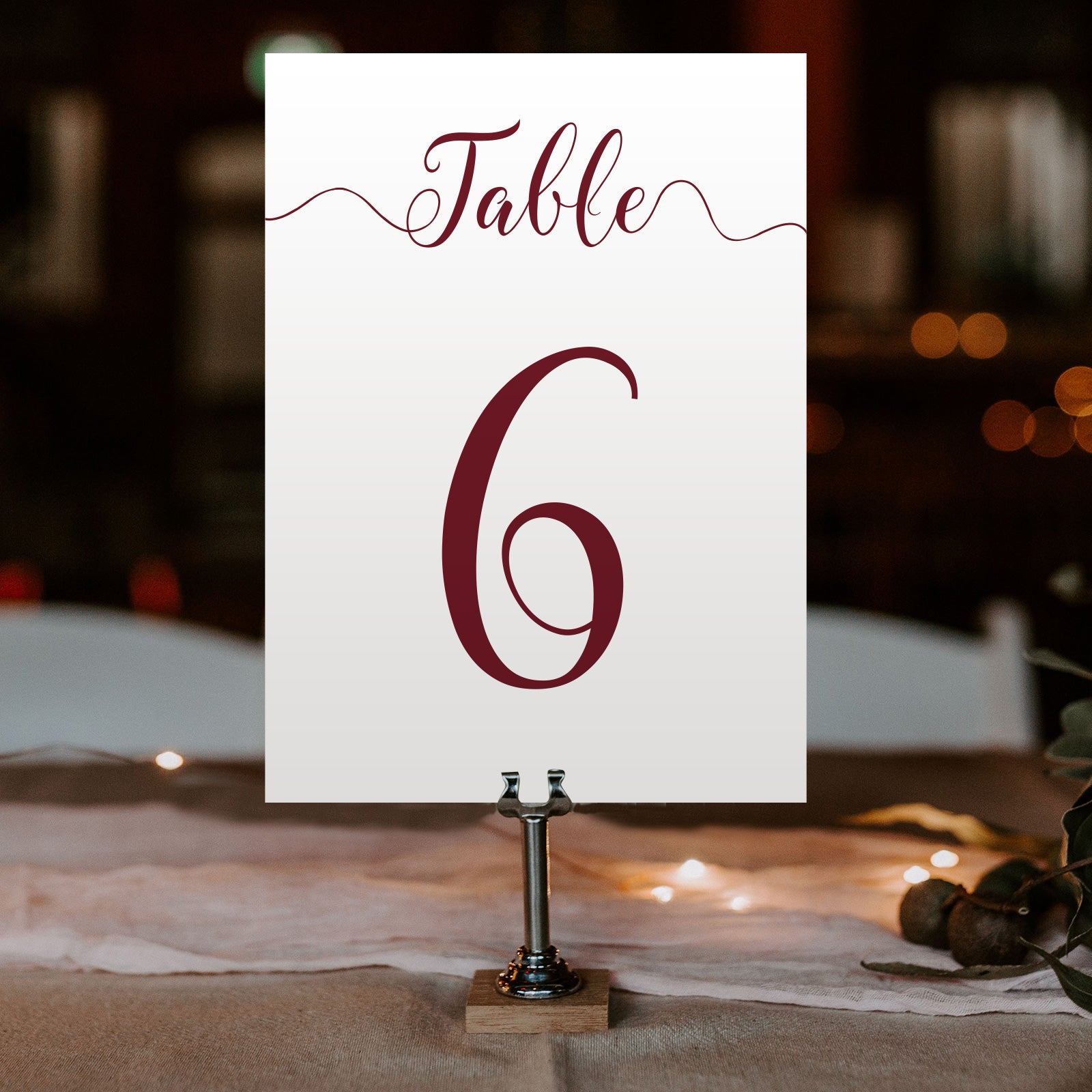 burgundy table number on a wedding table at an evening reception