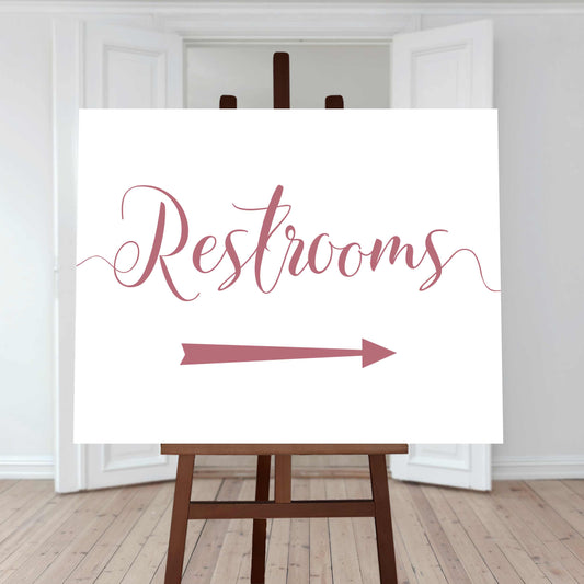 dusty pink restroom directions sign with an arrow pointing right