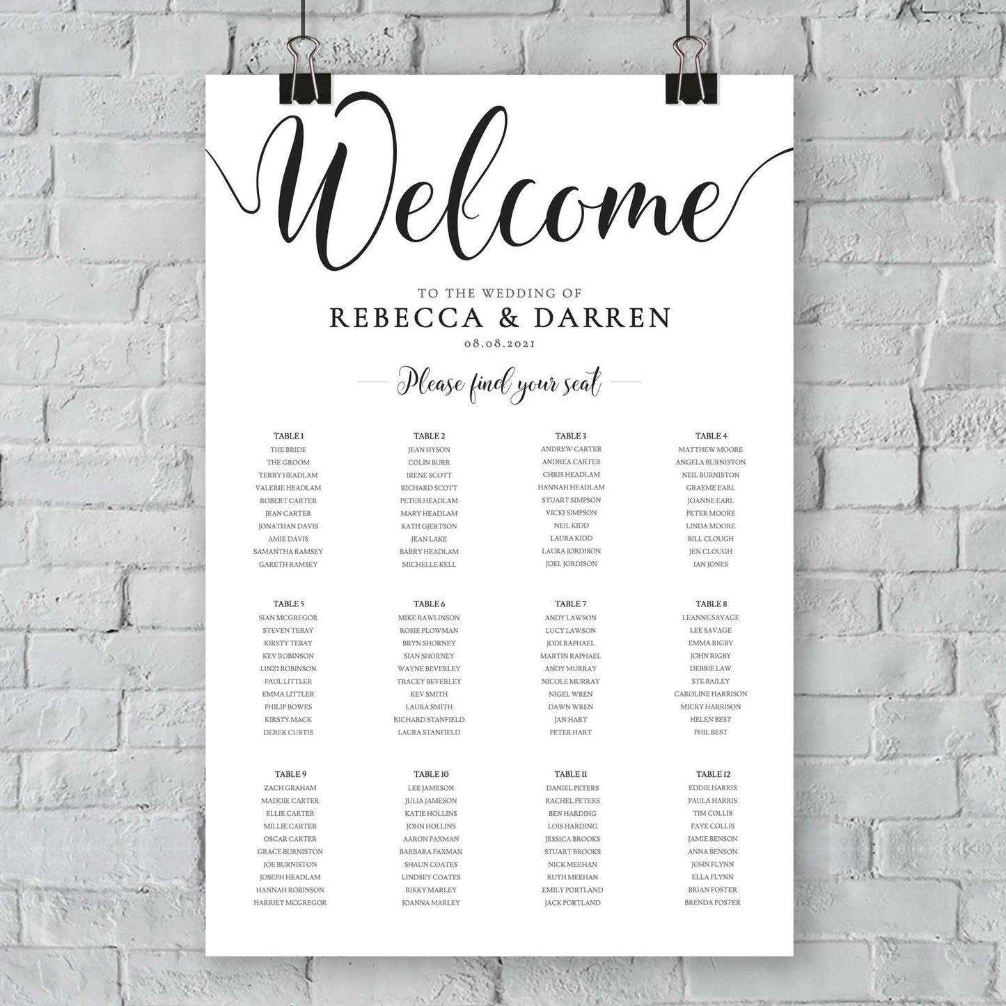 elegant minimalist seating chart hanging from a white brick wall