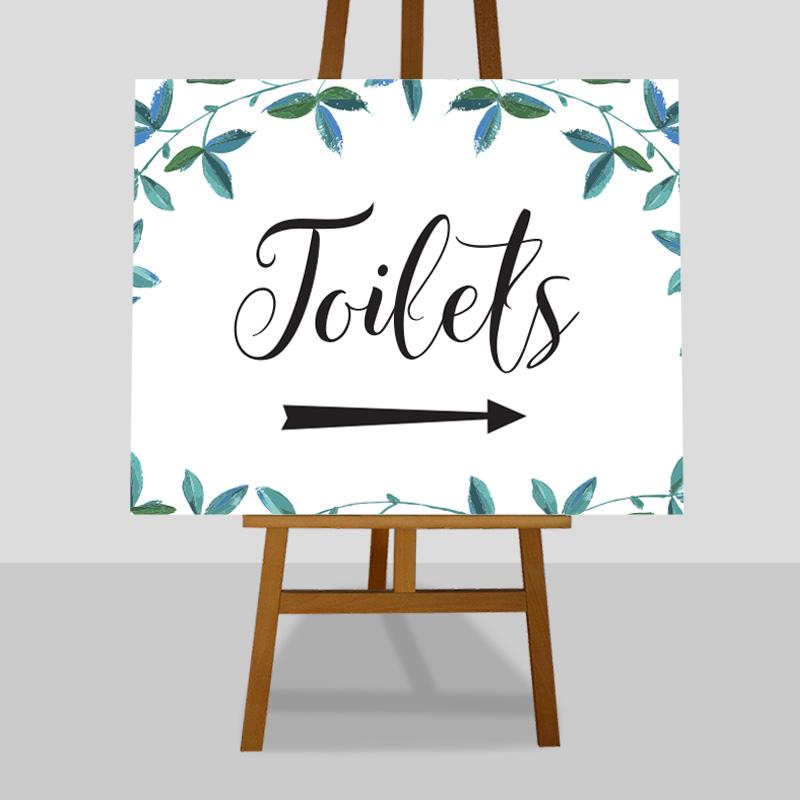large toilets arrow sign with eucalyptus leaves on an easel