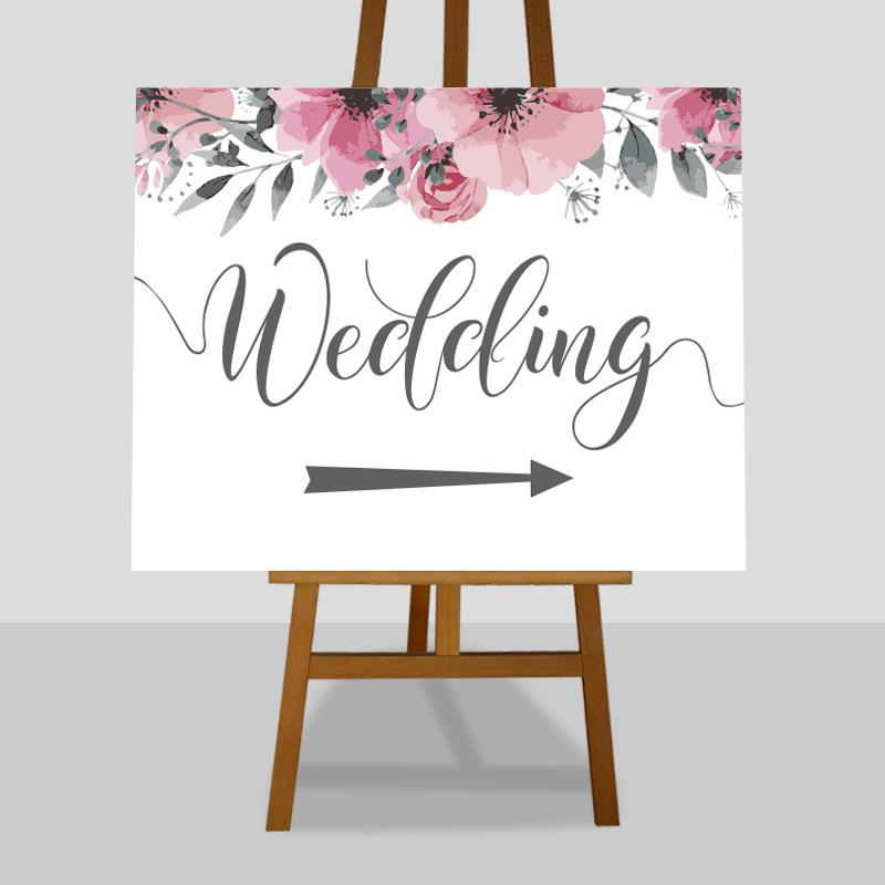wedding arrow sign with pink blossom flowers on an easel