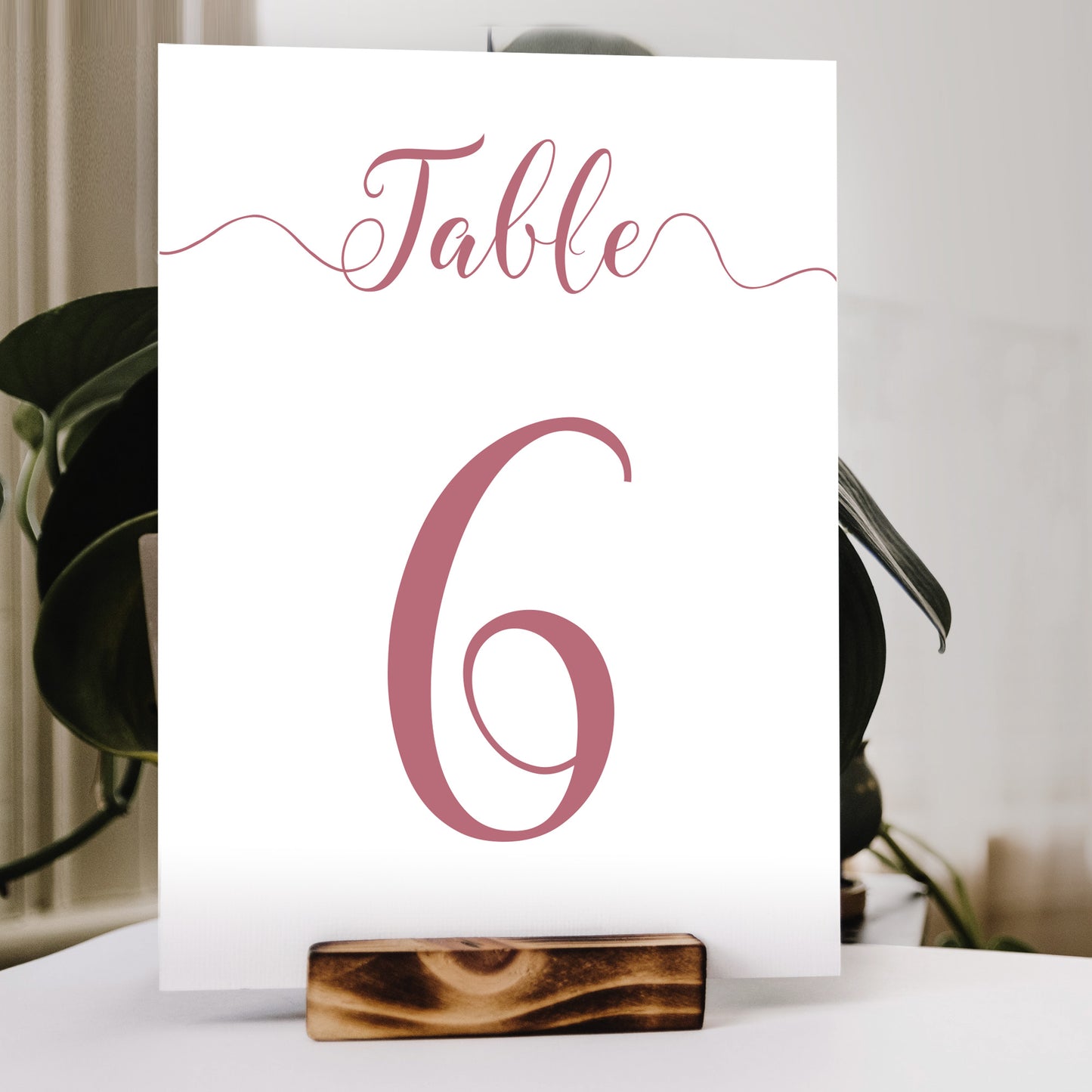fuchsia pink table number print in a wooden stand at a wedding