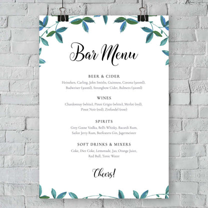 Garden bar menu with greenery border hanging on a white brick wall outside
