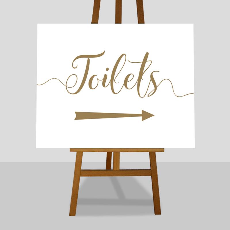 gold toilets sign with directional arrows printed on an easel