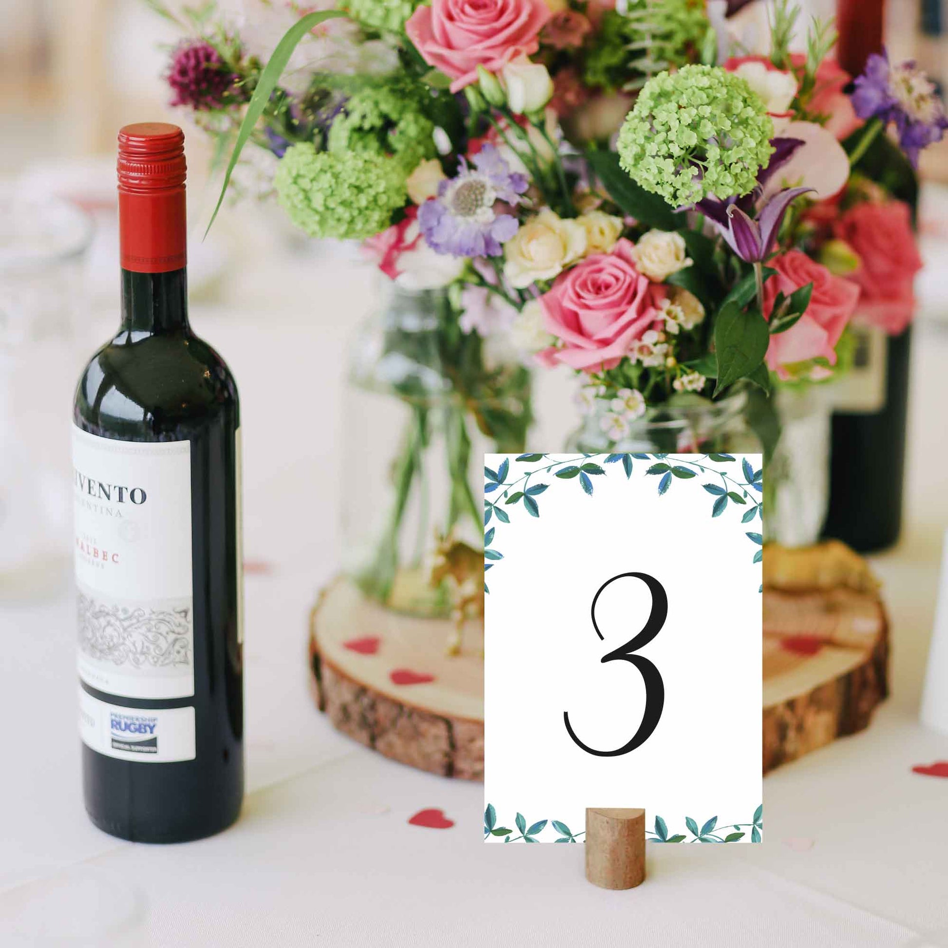 5x7 green foliage wedding table number next to a bottle of wine for scale