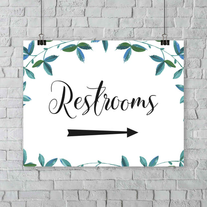 boho wedding restrooms right arrow sign with green foliage border hanging from an outdoor wall 