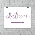 lavender purple wedding restrooms arrow signage hanging from a wall