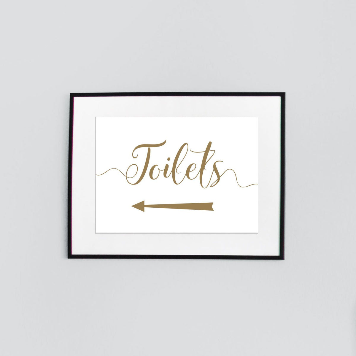 framed toilets sign with gold text and left arrow