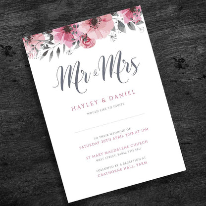 outdoor pink floral wedding invitation on a dark wood table