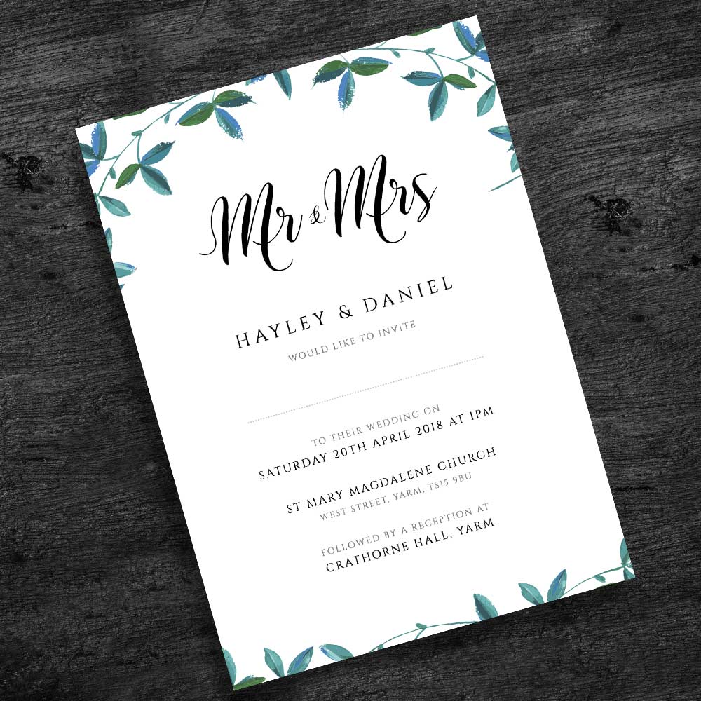 outdoor wedding invitation with green leaves border on a dark wood background