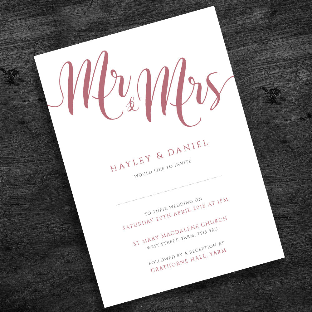 pale pink wedding invitation on wooden table