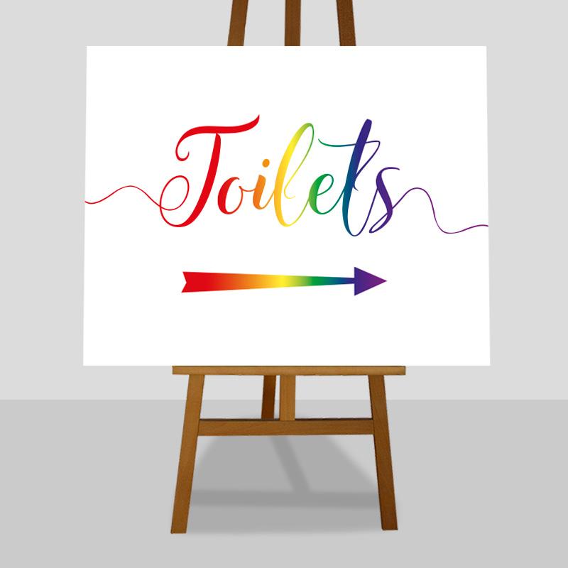 large toilet directions sign in rainbow colours on an easel