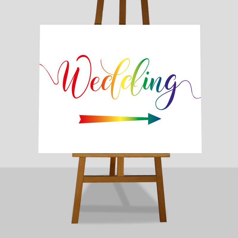large rainbow wedding directions sign on an easel