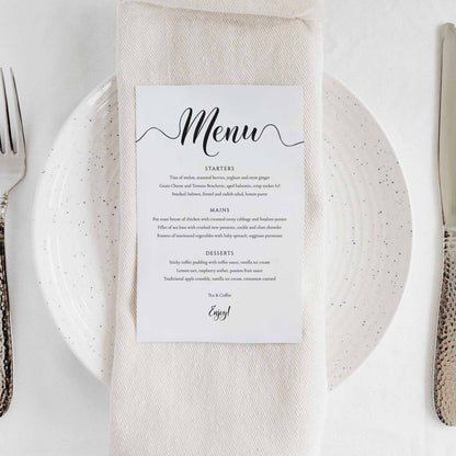 Minimalist wedding menu card placed on top of a napkin, on a plate on a wedding table