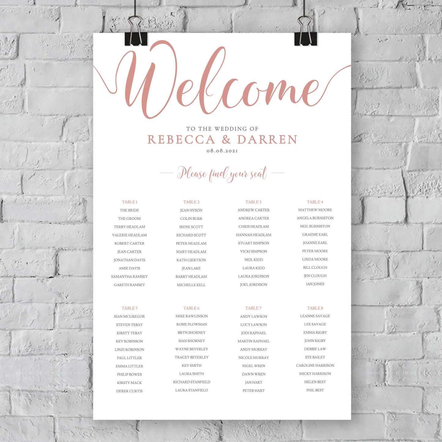 rose gold table plan hanging from white brick wall