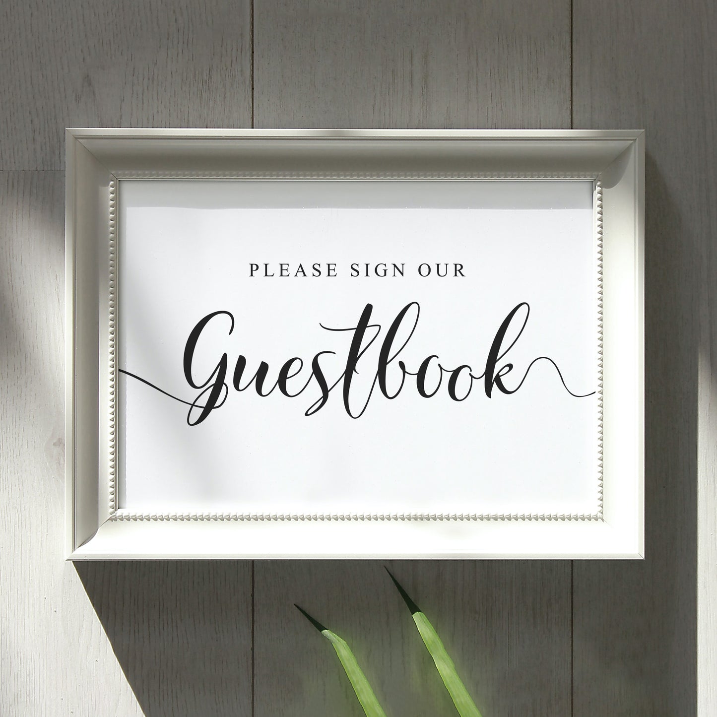 Please sign our guest book black and white wedding sign on a wall