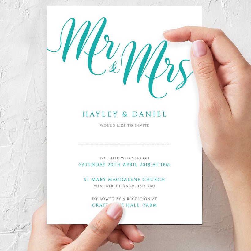 woman holding turquoise wedding invitation in hands